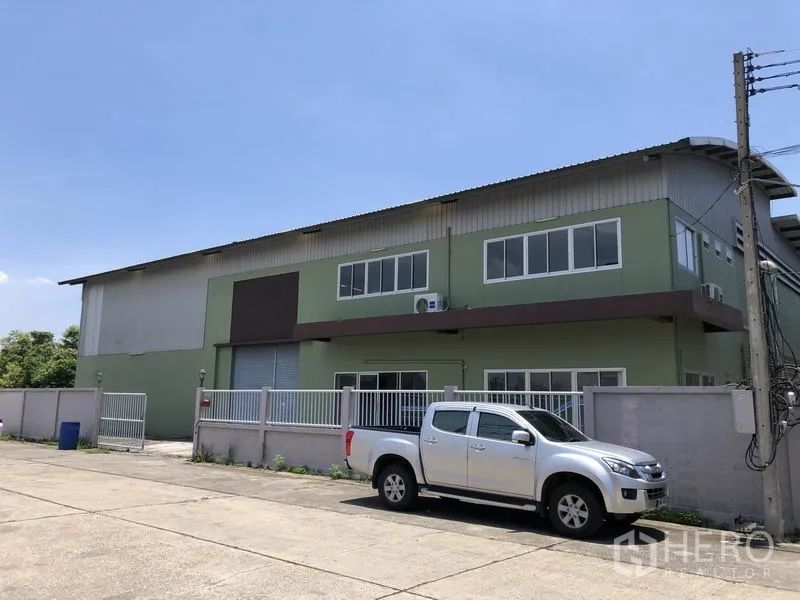 Factory for rent in Pathum Thani - Front exterior of factory showing fence, parking and loading roller shutter.