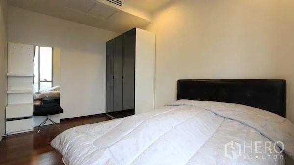 Condominium for rent - Bedroom angle showing wardrobe, mirror and warm wooden floors.