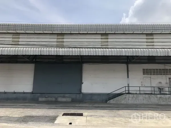 货栈 出租在Khlong Luang, Pathum Thani - 仓库外立面，带长雨棚的抬高装卸平台和大型滑动门，卡车进出便捷。