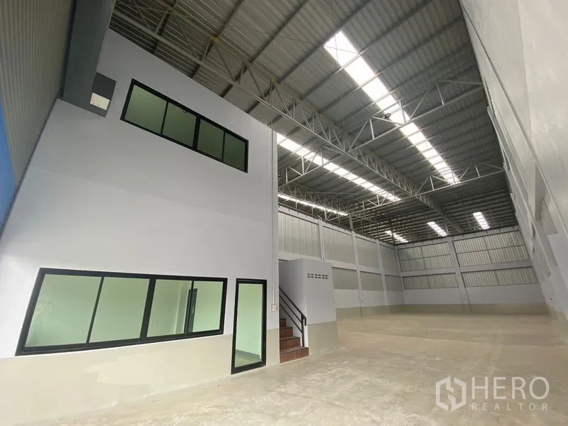 Warehouse for rent in Pathum Thani - Warehouse interior with high-clearance steel roof, skylights, and a built-in office block.
