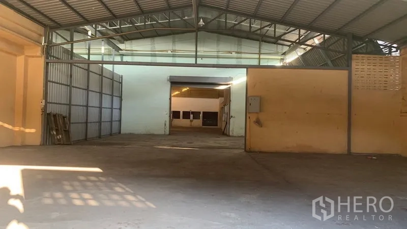 Warehouse for rent in Mueang Nakhon Pathom, Nakhon Pathom - Wide central opening leading to an inner bay with sliding metal gate and partition walls.