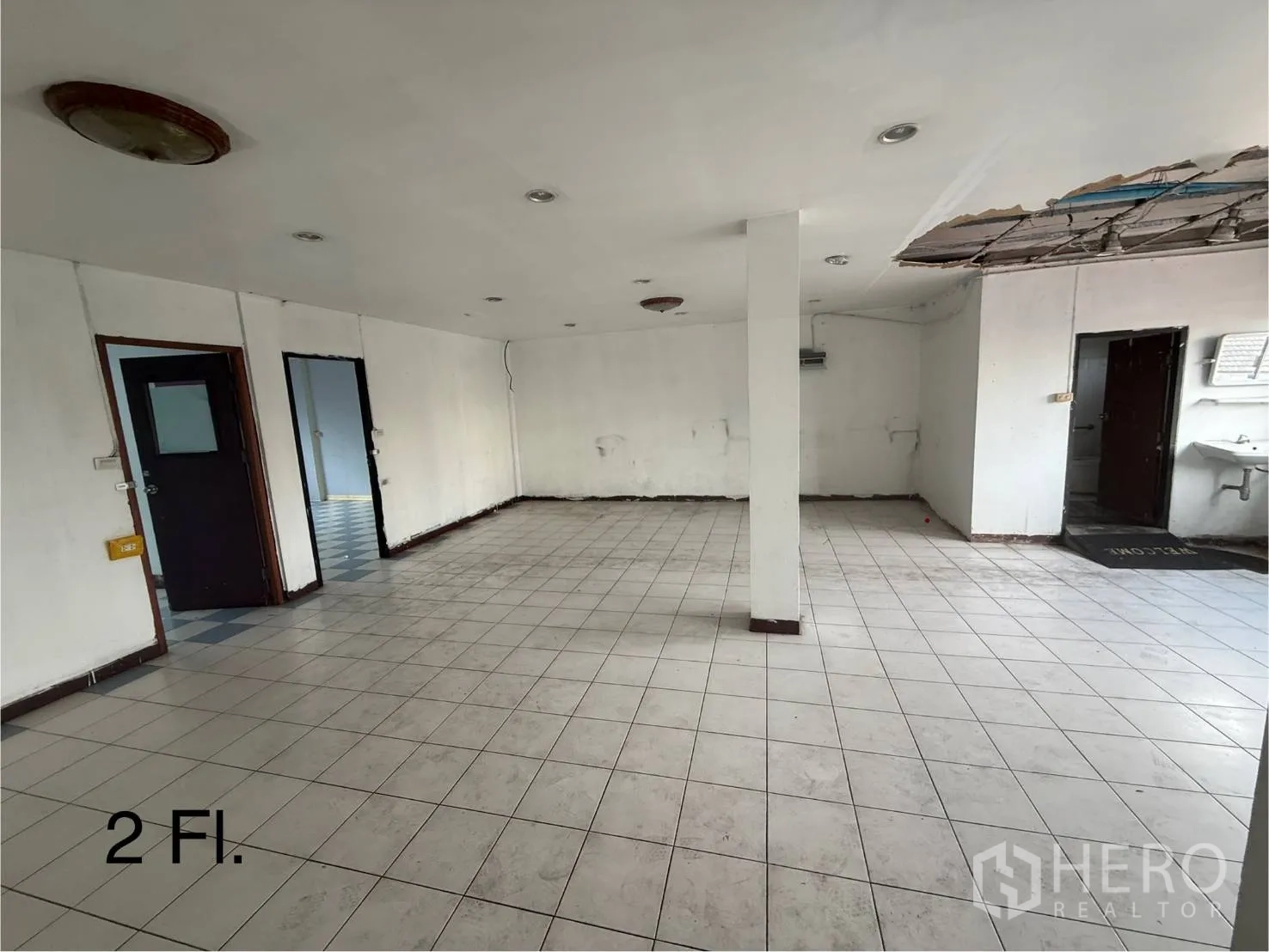 Shophouse for rent in Bang Na, Bangkok - Second-floor open-plan area with white tiles, central column, and multiple doorways.