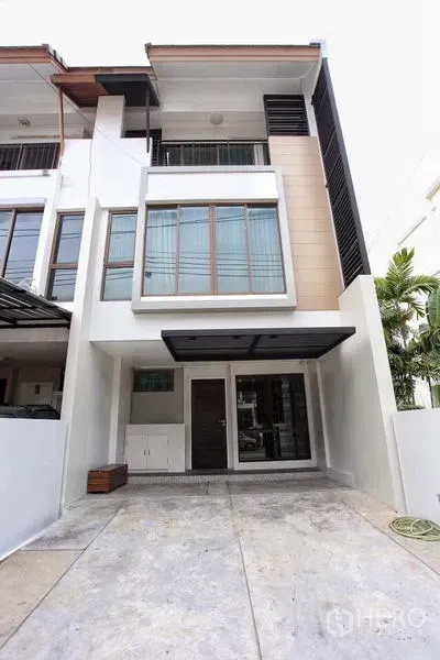 Townhouse for rent in Phra Khanong, Bangkok - Modern three-storey townhouse facade with wide windows and a covered carport.
