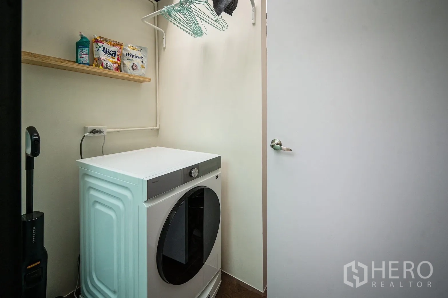 Townhouse for rent in Bang Phli, Samut Prakan - Compact laundry room with a front-load washer, shelf and hanging rack.