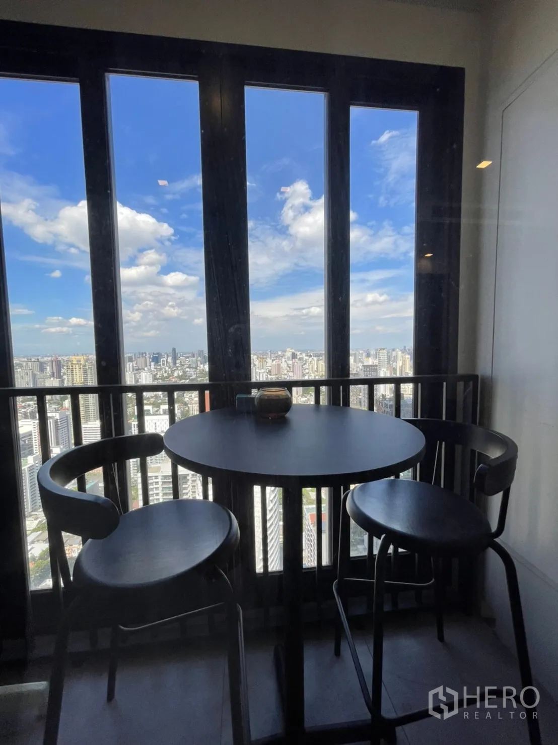 คอนโด for rent in Watthana, Bangkok - ระเบียงกระจกพร้อมโต๊ะกลมและสตูล มองเห็นวิวสกายไลน์ของเมือง