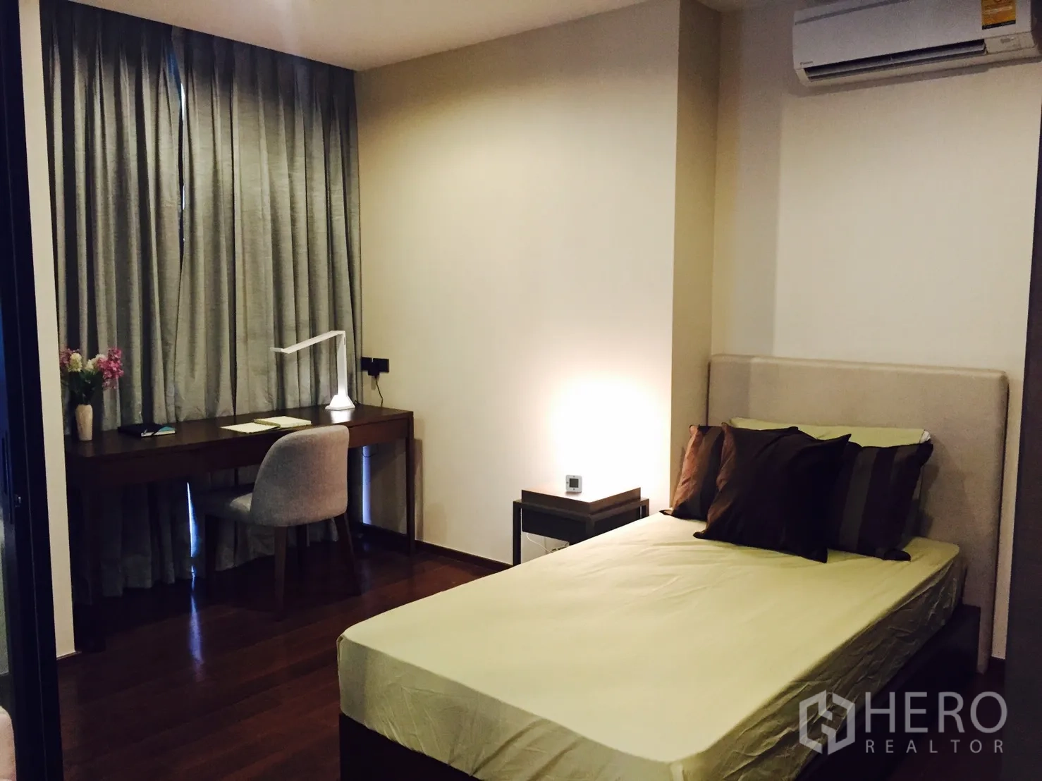 Condominium for rent or sale in Sathon, Bangkok - Cozy bedroom with a work desk by full-length curtains, soft lighting, and wood floors.