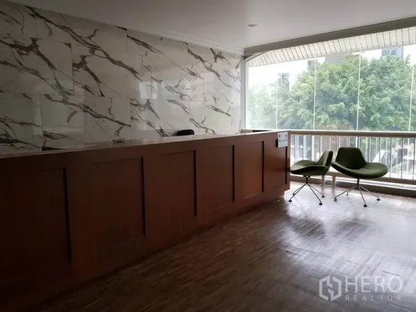 Retail Space for rent in Khlong Toei, Bangkok - Reception counter with marble wall and lounge chairs beside a large window with treetop views.