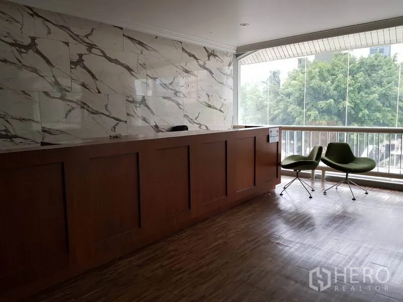 Retail Space for rent in Khlong Toei, Bangkok - Reception counter with marble wall and lounge chairs beside a large window with treetop views.