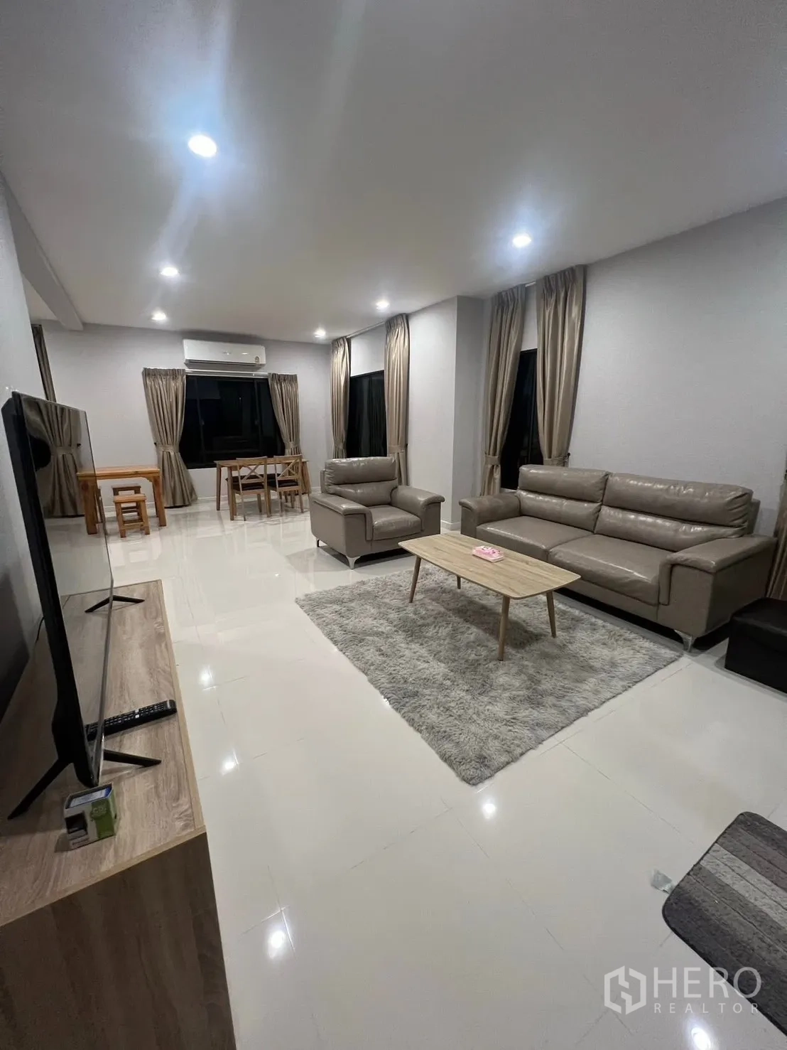 บ้าน ให้เช่าในBang Phli, Samut Prakan - พื้นที่รับแขกและทานอาหารแบบเปิด พร้อมโซฟา พรม ทีวี และไฟดาวน์ไลต์ยามค่ำ