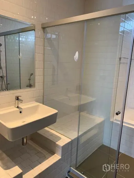 Condominium for rent in Watthana, Bangkok - Modern bathroom with wall mirror, square vanity and glass-enclosed shower with a tiled bench.