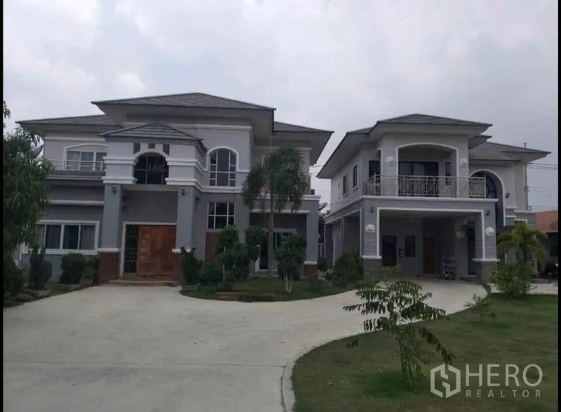 บ้าน ขายในLam Luk Ka, Pathum Thani - ภาพมุมกว้างเห็นบ้านสองหลัง สนามหญ้าและถนนโค้ง