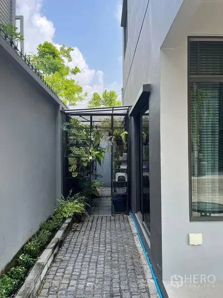 联排别墅 出租在Saphan Sung, Bangkok - 联排别墅侧边小院，鹅卵石步道与垂直绿植，带金属棚架。