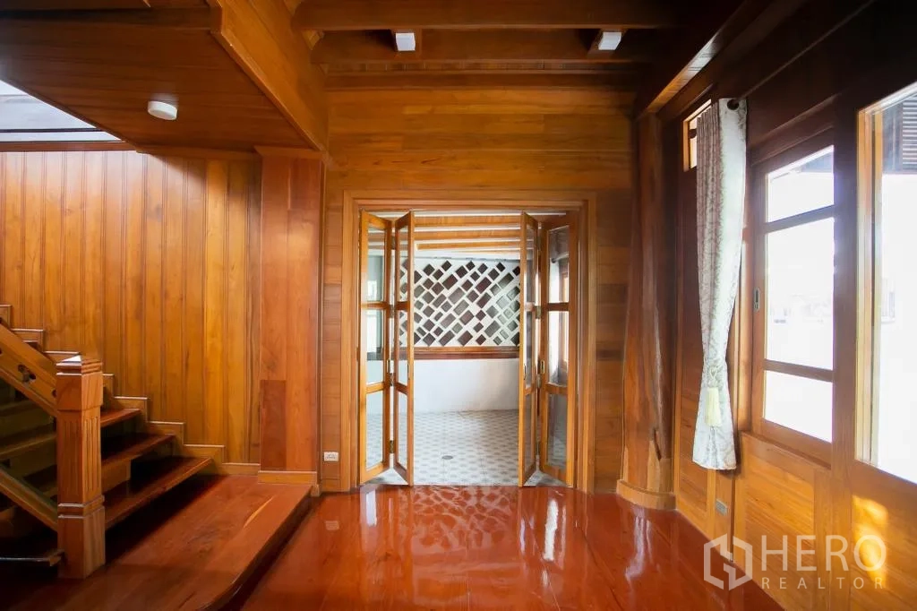 独栋房屋 for rent or sale in Huai Khwang, Bangkok - 木质大厅通过折叠玻璃门连通半户外铺砖空间。