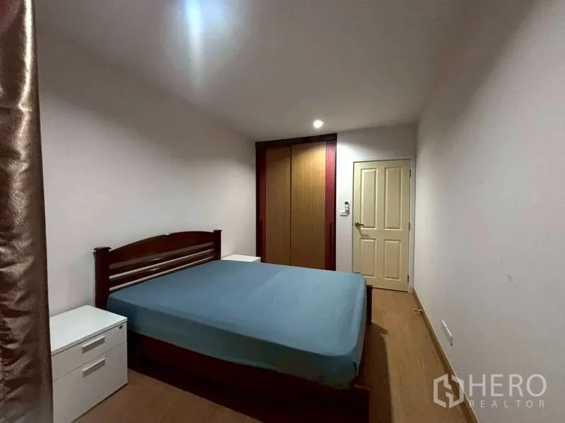 Townhouse for rent in Suan Luang, Bangkok - Bedroom with bed, bedside tables, and built-in wardrobe.