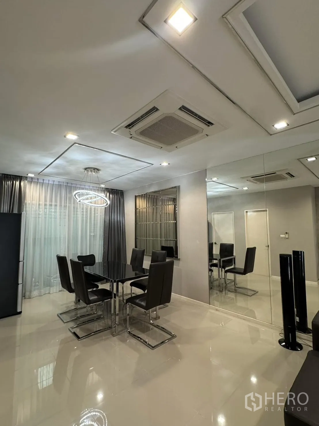 Townhouse for rent in Suan Luang, Bangkok - Dining area with black glass table, six leather chairs and modern ring chandelier.