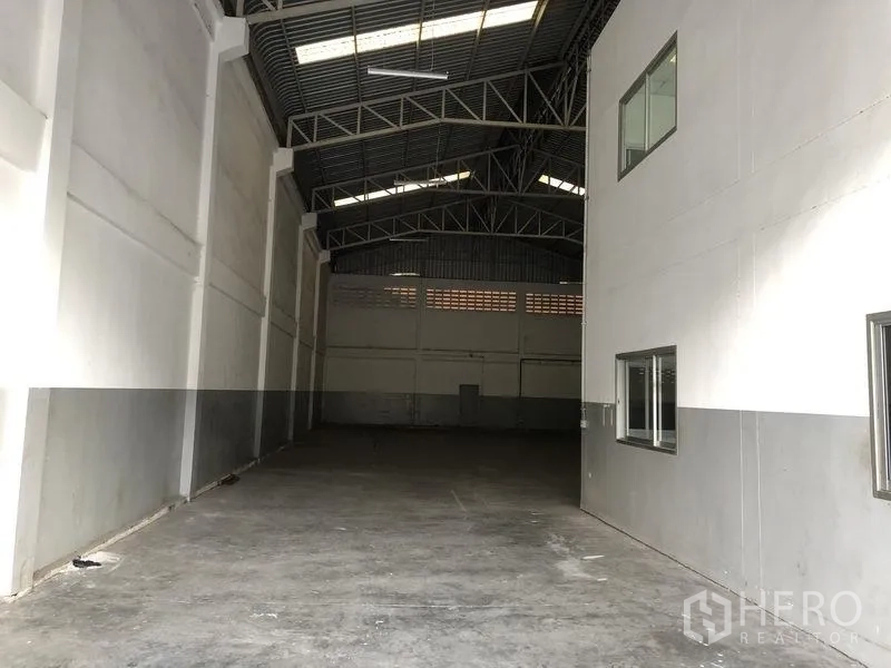 工厂 出租在Pathum Thani - 仓库长通道，紧邻办公室区，高墙与混凝土地面。