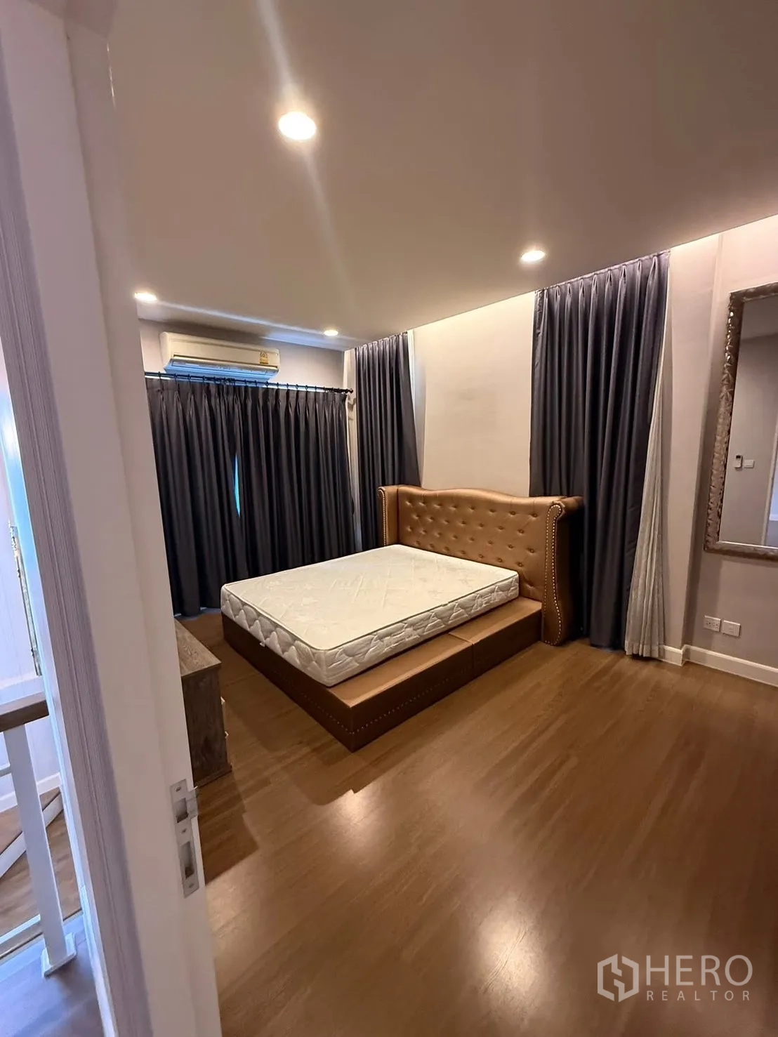 Detached House for rent in Prawet, Bangkok - Cozy bedroom with wooden flooring, upholstered bedframe and blackout curtains.