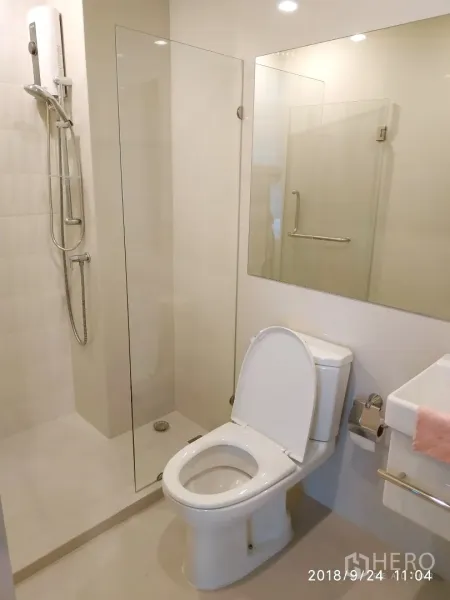 คอนโด ให้เช่าในHuai Khwang, Bangkok - ห้องน้ำสไตล์โมเดิร์น กั้นอาบน้ำกระจก โถสุขภัณฑ์ และกระจกบานใหญ่พร้อมไฟดาวน์ไลท์.