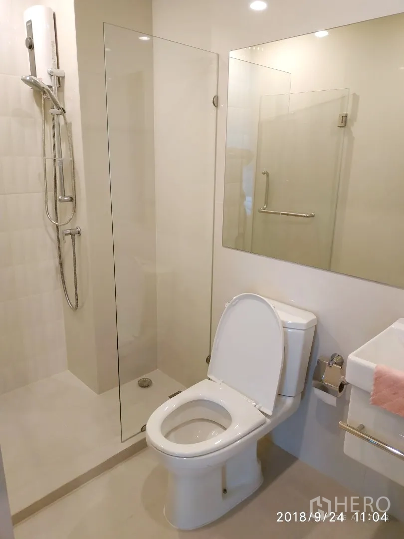 คอนโด ให้เช่าในHuai Khwang, Bangkok - ห้องน้ำสไตล์โมเดิร์น กั้นอาบน้ำกระจก โถสุขภัณฑ์ และกระจกบานใหญ่พร้อมไฟดาวน์ไลท์.