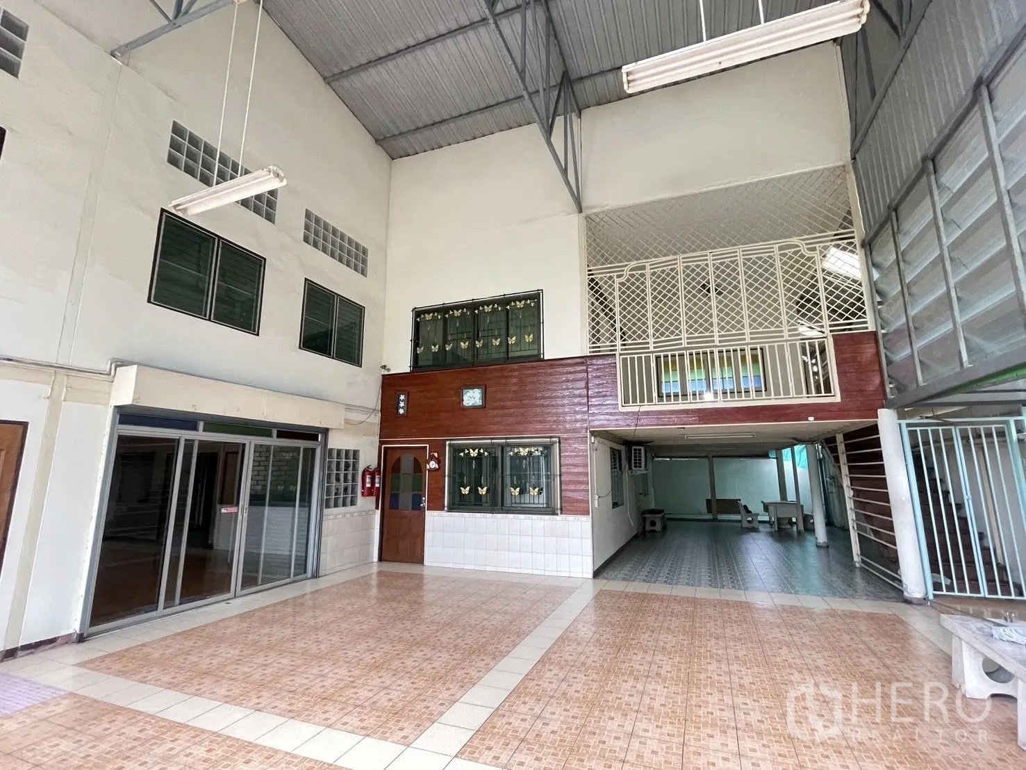 Warehouse for rent in Lat Phrao, Bangkok - High-ceiling entrance hall with mezzanine, tiled floors and sliding glass doors.