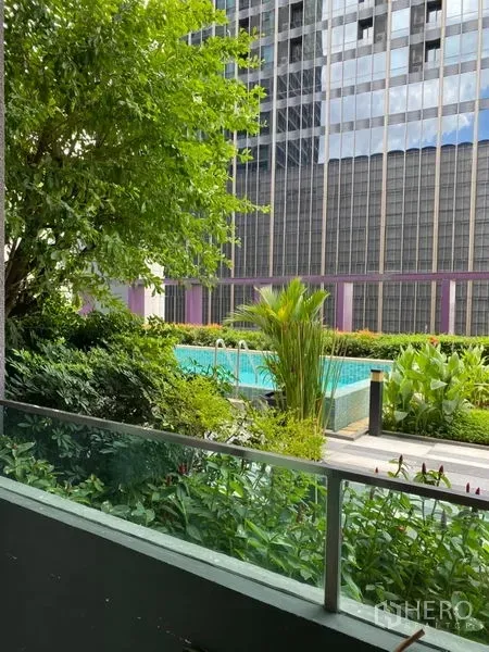 Condominium for rent in Khlong Toei, Bangkok - Private balcony overlooking lush gardens and a condominium swimming pool with city towers beyond.
