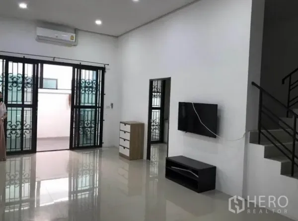 联排别墅 出租在Wang Thonglang, Bangkok - 宽敞客厅，装有空调与电视柜，推拉门连接露台。