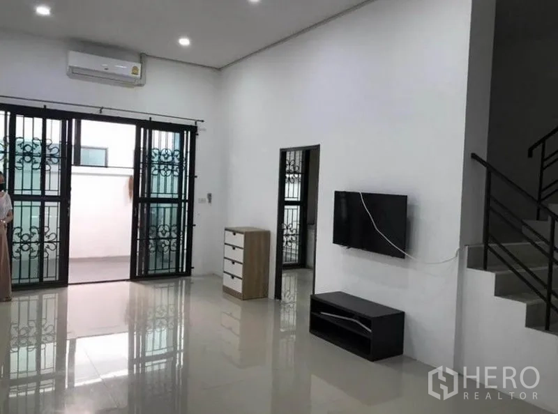 联排别墅 出租在Wang Thonglang, Bangkok - 宽敞客厅，装有空调与电视柜，推拉门连接露台。