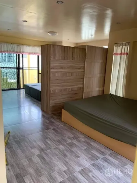 Townhouse for rent in Phra Khanong, Bangkok - Spacious bedroom with wood-look tiles, a wooden partition wardrobe, and balcony access in a Bang Chak townhouse.