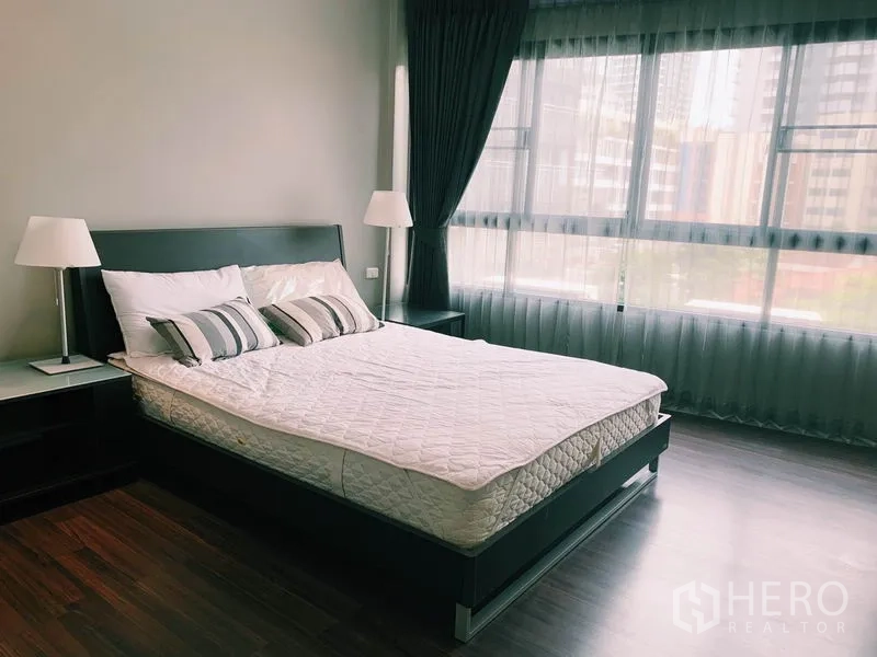 公寓 出租在Watthana, Bangkok - 宽敞主卧，落地窗与纱帘、木地板与现代床架。