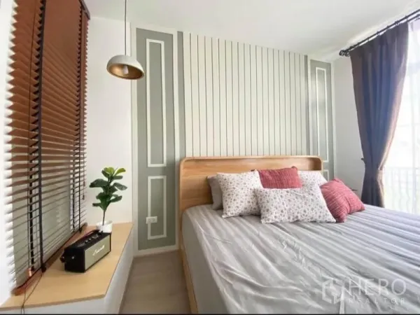 Townhouse for rent in Prawet, Bangkok - Bright bedroom with paneled feature wall, large window, wooden bed and pendant light.