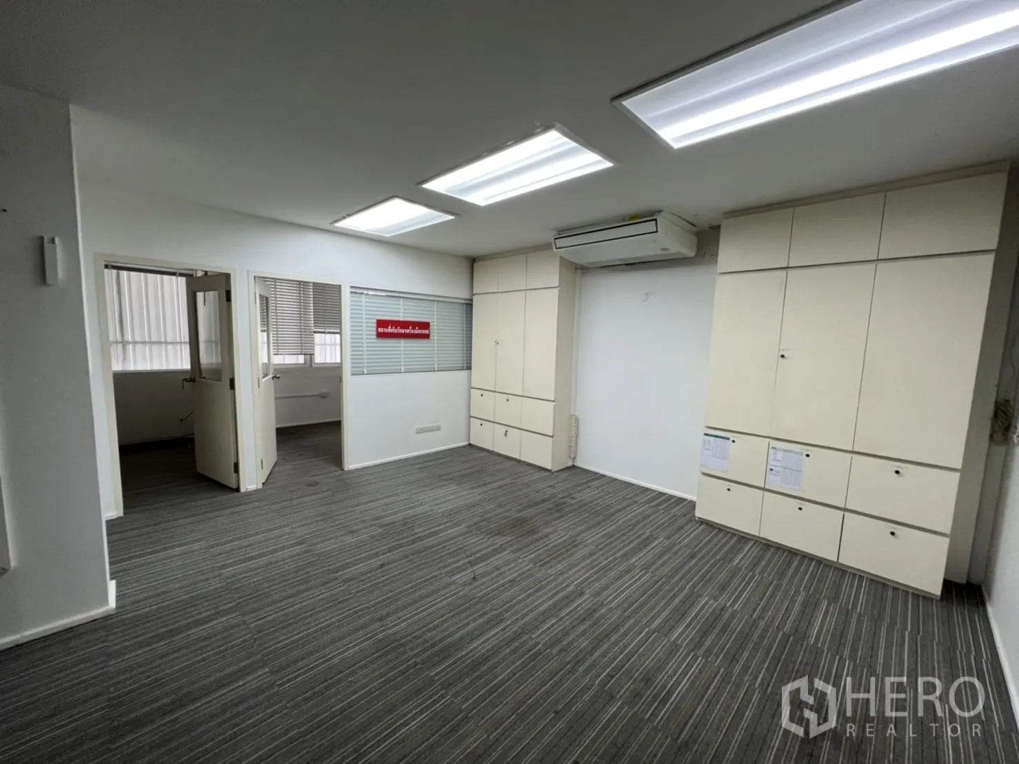 Shophouse for rent or sale in Watthana, Bangkok - Open-plan office with bright ceiling lights, air conditioning and storage cabinets.