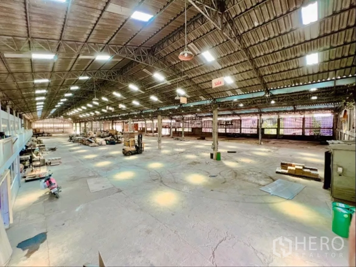 Factory for rent in Sai Noi, Nonthaburi - Expansive production hall with high steel truss roof, skylights, and bright lighting.