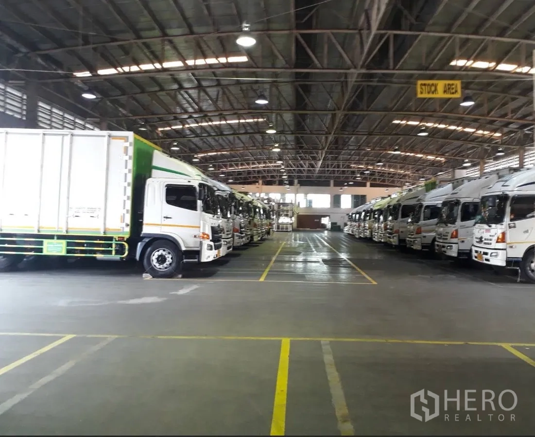 Factory for rent or sale in Uthai, Phra Nakhon Si Ayutthaya - Large warehouse interior with high steel roof, bright lighting and marked bays filled with trucks.
