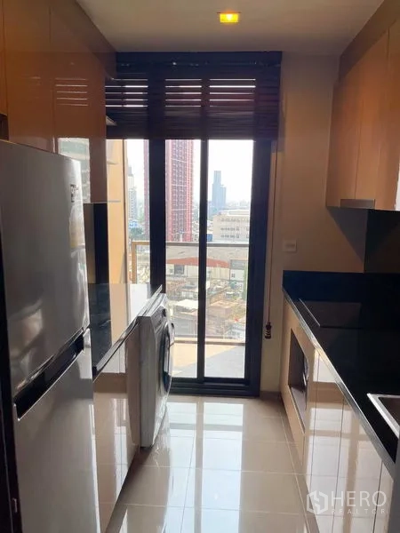 公寓 出售在Watthana, Bangkok - 独立走廊式厨房，高窗、冰箱、洗衣机与收纳柜。