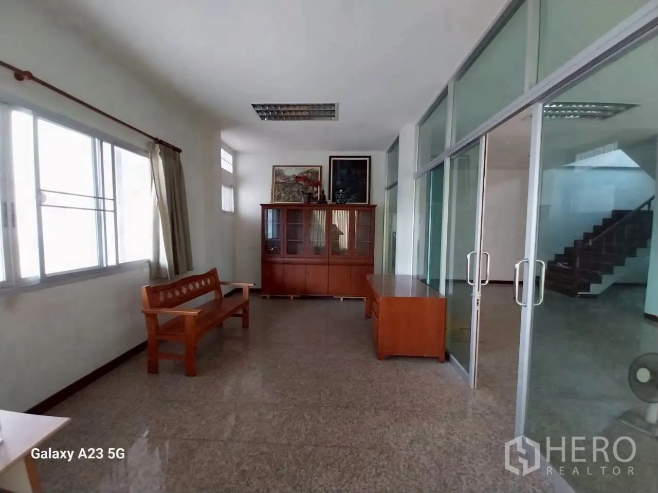Factory for rent in Phra Samut Chedi, Samut Prakan - Ground-floor lobby with sliding glass doors, windows, and simple wooden furniture.