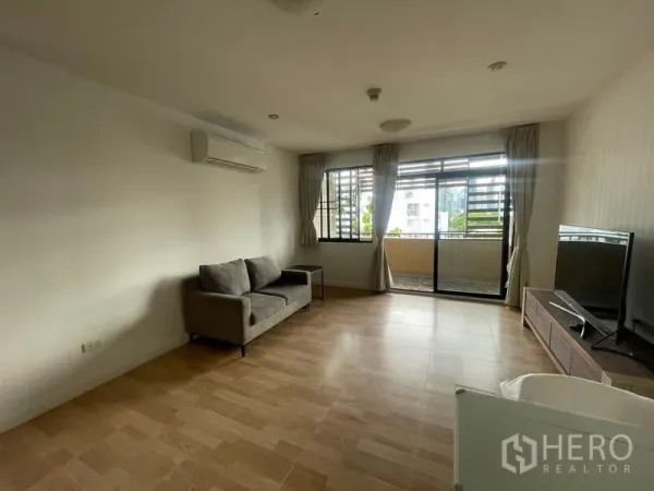 Condominium for rent in Watthana, Bangkok - Bright living area with sofa, air-conditioning and sliding doors opening to a balcony.