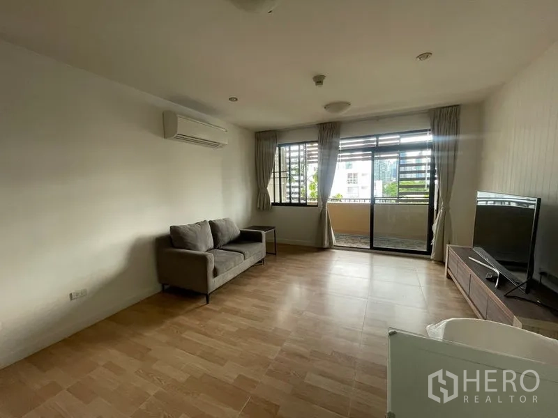 Condominium for rent in Watthana, Bangkok - Bright living area with sofa, air-conditioning and sliding doors opening to a balcony.