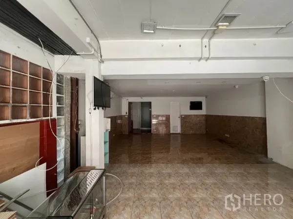 带办公室的家 出租在Watthana, Bangkok - 一层开放式空间，亮面地砖、白色天花与玻璃砖装饰，适合展示或接待。
