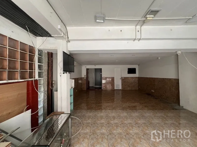 带办公室的家 出租在Watthana, Bangkok - 一层开放式空间，亮面地砖、白色天花与玻璃砖装饰，适合展示或接待。