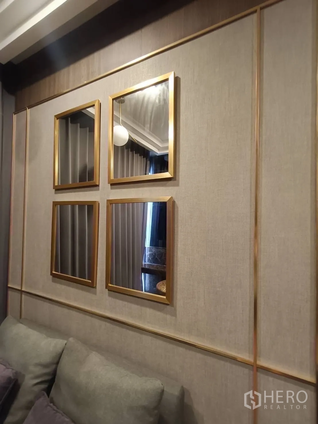 Condominium for rent in Bang Rak, Bangkok - Close view of the living room wall with four gold-framed mirrors above a sofa.
