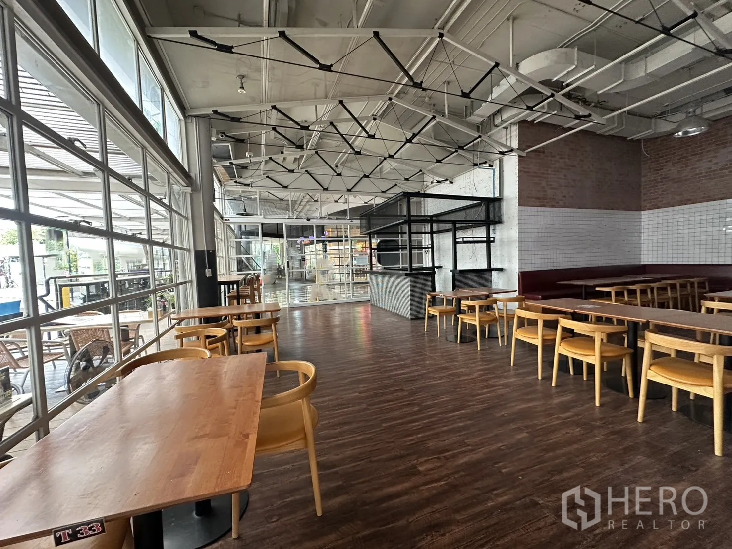 Retail Space for rent in Watthana, Bangkok - Open-plan interior with large windows, wood floors, and dining-style tables and chairs.