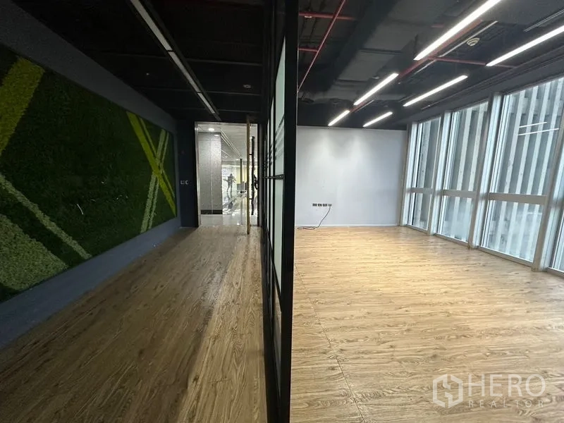 办公空间 出租在Bang Rak, Bangkok - 走廊绿植墙与明亮落地窗房间的对比视角