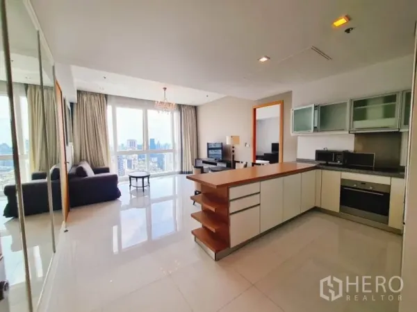Condominium for rent in Khlong Toei, Bangkok - Open-plan living room with a wood-topped island kitchen, floor-to-ceiling windows and skyline view.