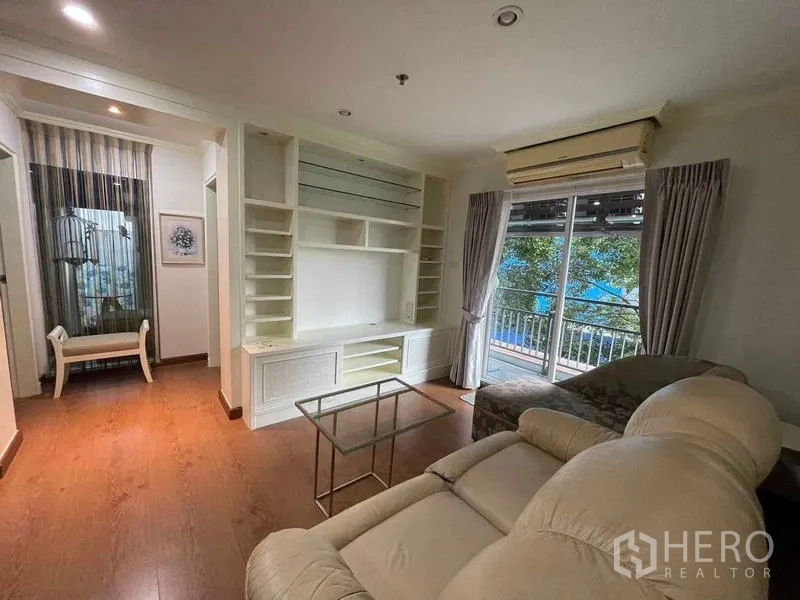 Condominium for rent - Bright living room with built-in media wall, sofa set and balcony with leafy pool view.