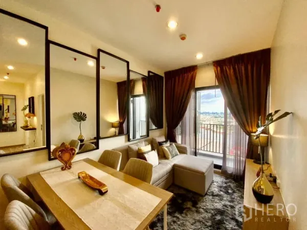 คอนโด ให้เช่าหรือขายในThon Buri, Bangkok - ห้องนั่งเล่นติดกระจกเงา โซฟาเข้ามุม ผ้าม่านทึบ มองออกสู่ระเบียง
