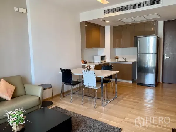 Condominium for rent in Khlong Toei, Bangkok - Cozy dining nook beside an L-shaped kitchen with built-in cabinets and appliances.