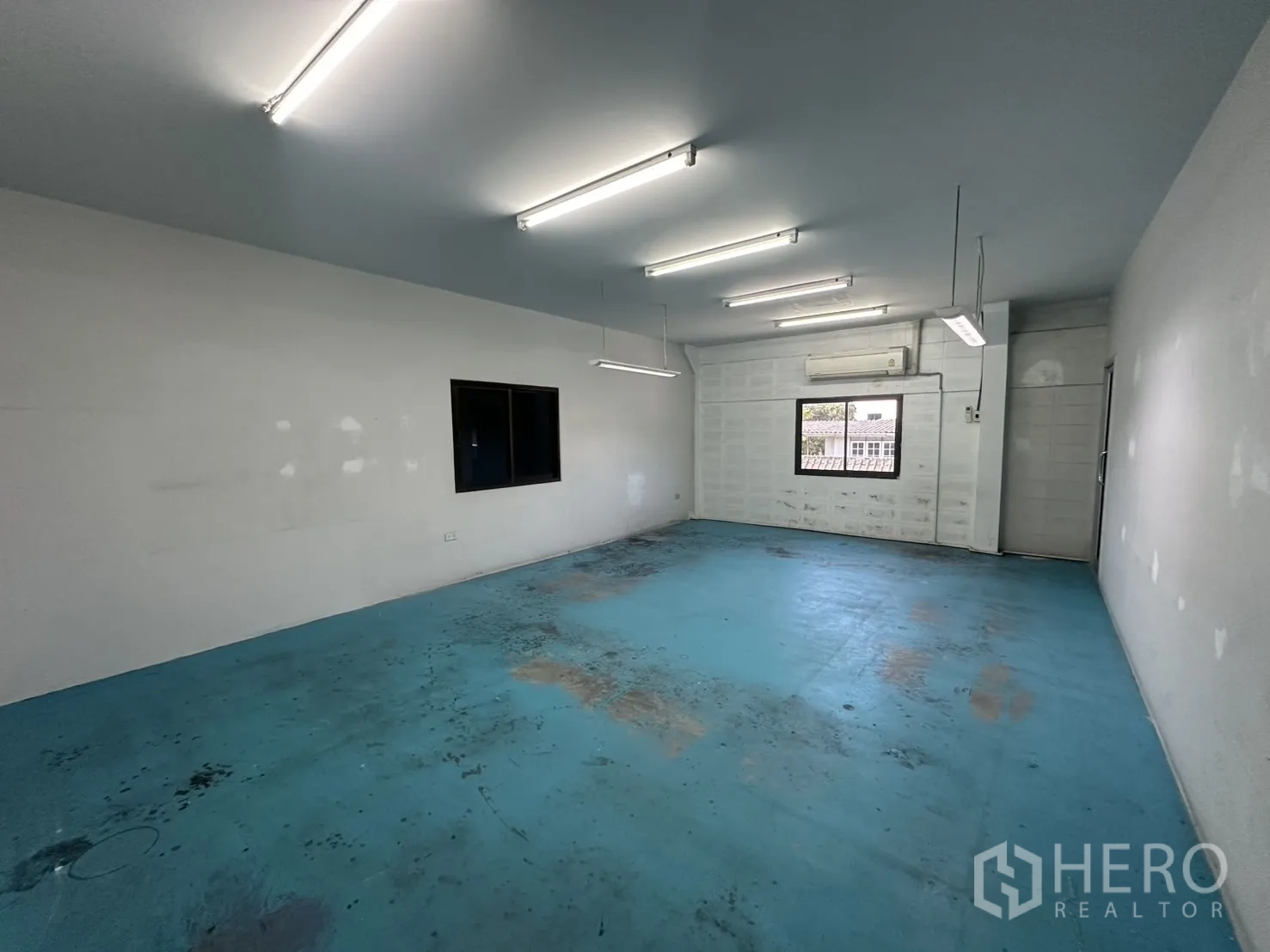 Warehouse for rent in Bang Na, Bangkok - Air-conditioned studio room with blue floor and bright lighting.