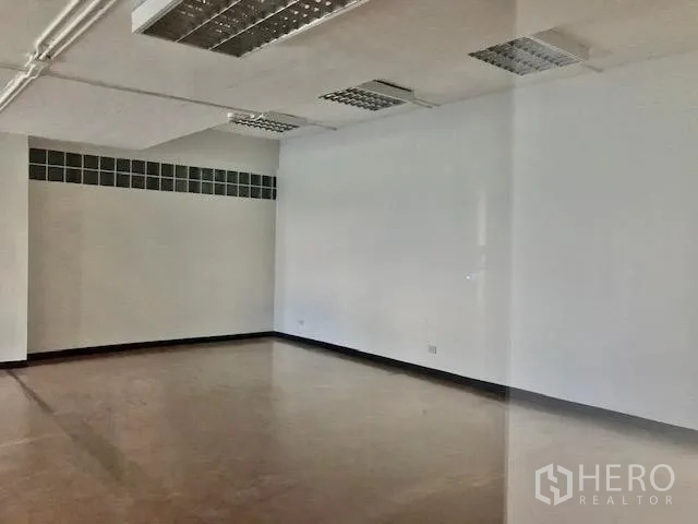 Office Space for rent in Watthana, Bangkok - Bright white-walled office corner with fluorescent ceiling panels and a glass-block window strip.