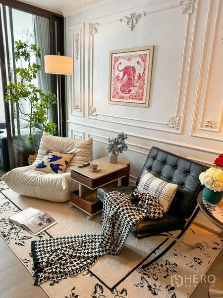 Condominium for rent - Lounge corner with accent chairs, wall mouldings, floor lamp and greenery by full‑height windows.