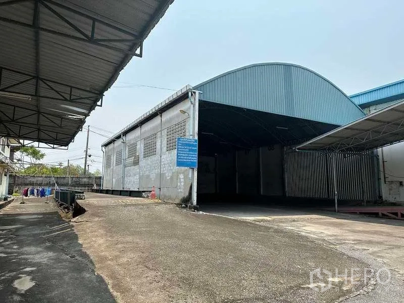 Factory for rent or sale in Bang Phli, Samut Prakan - Exterior of arched-roof warehouse with driveway, canopy and loading areas.